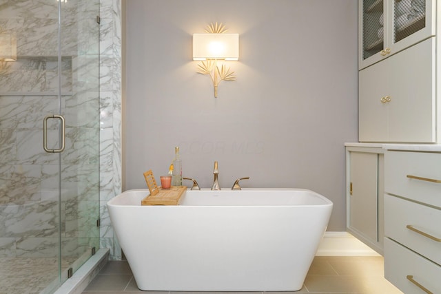 full bath featuring a freestanding tub, a marble finish shower, and tile patterned floors