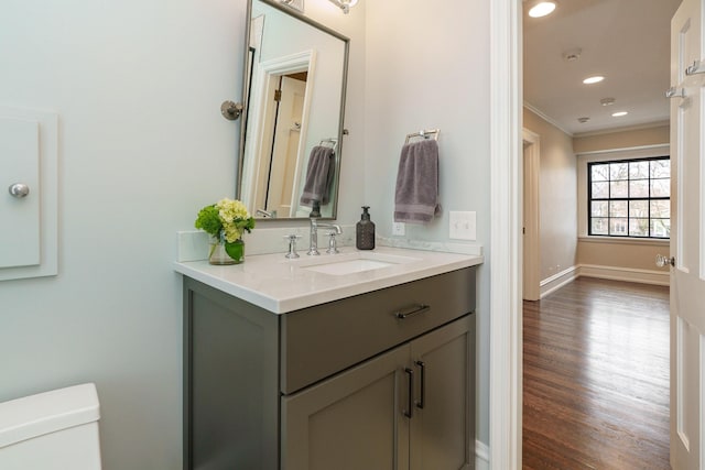 bathroom with crown molding, toilet, vanity, wood finished floors, and baseboards