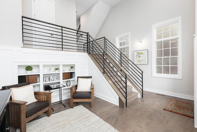 stairs featuring a towering ceiling, baseboards, and wood finished floors