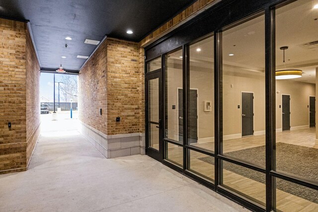 corridor with visible vents, elevator, brick wall, french doors, and concrete floors