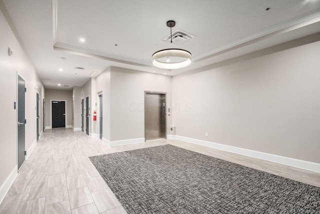 spare room featuring elevator, baseboards, visible vents, and a raised ceiling