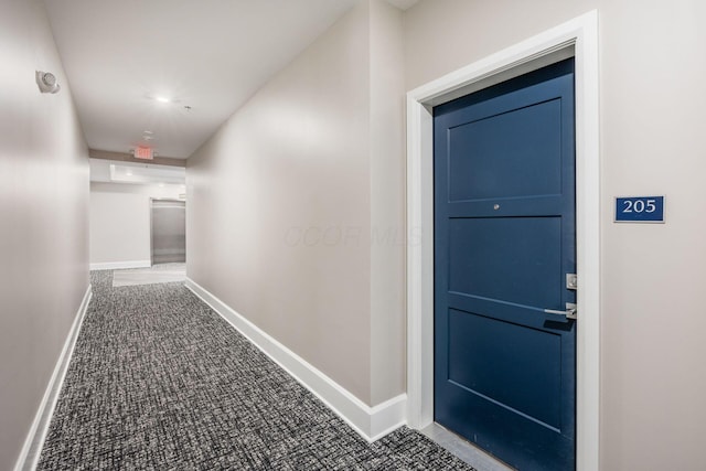 corridor featuring baseboards and carpet flooring