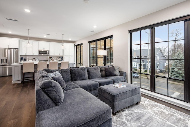 living area featuring dark wood-style floors, recessed lighting, a healthy amount of sunlight, and visible vents