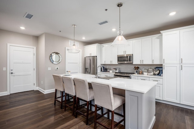 kitchen with appliances with stainless steel finishes, visible vents, an island with sink, and a kitchen breakfast bar