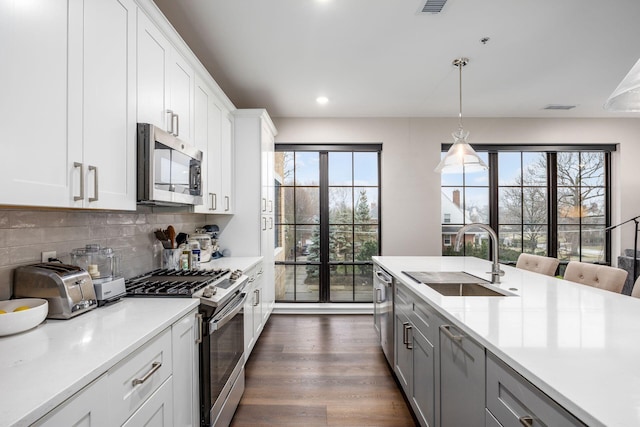 kitchen with stainless steel appliances, light countertops, a sink, and tasteful backsplash