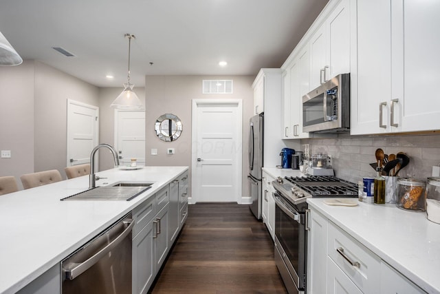 kitchen featuring stainless steel appliances, light countertops, a sink, and visible vents