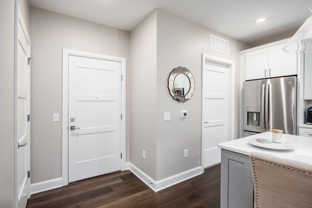 kitchen featuring dark wood-style floors, light countertops, stainless steel fridge, and white cabinets