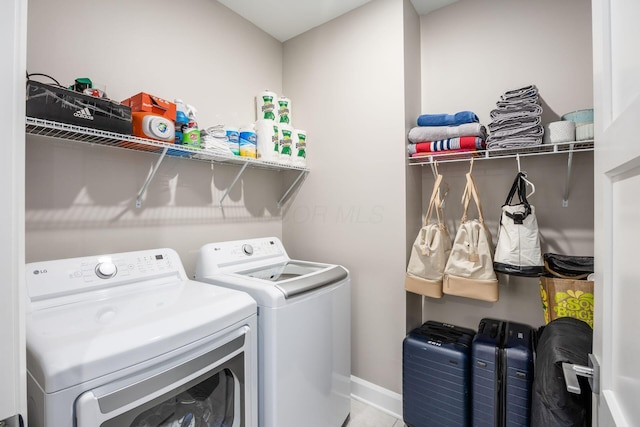 washroom featuring laundry area, baseboards, and washer and dryer