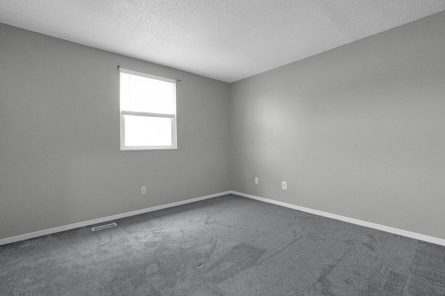 empty room featuring visible vents, carpet flooring, a textured ceiling, and baseboards