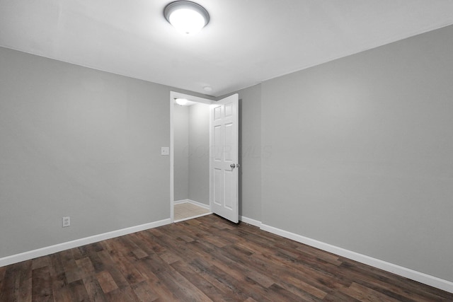 unfurnished room with baseboards and dark wood-type flooring