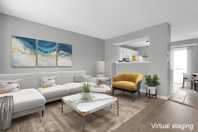 living area featuring a textured ceiling, baseboards, and light wood-style floors