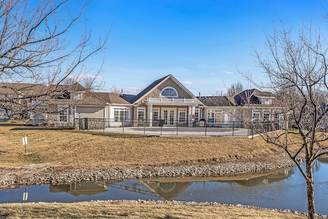 back of property featuring a water view and fence