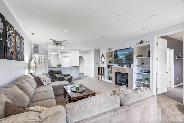 carpeted living room with a ceiling fan, baseboards, visible vents, and a tiled fireplace