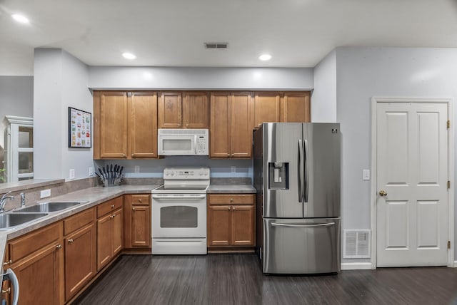 kitchen with white appliances, a sink, visible vents, brown cabinets, and dark wood-style floors