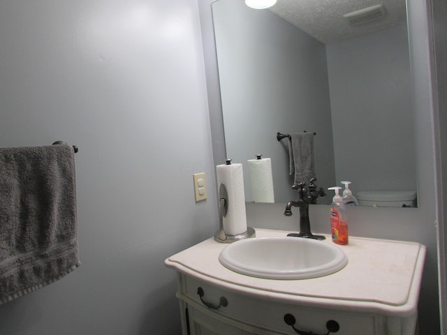 bathroom featuring visible vents, a textured ceiling, and vanity