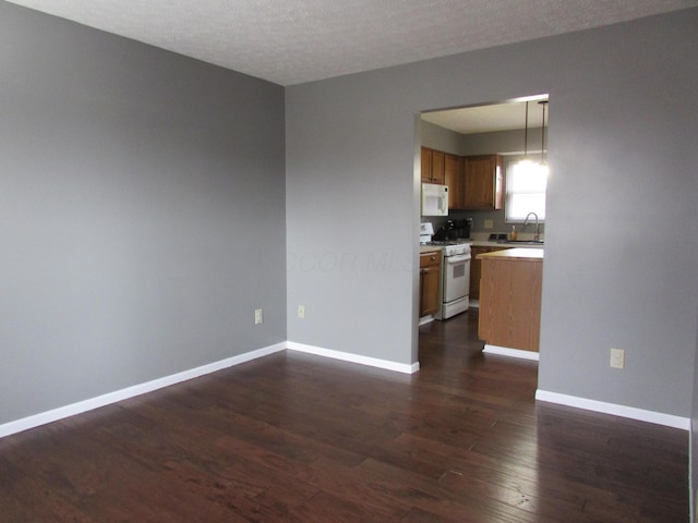 interior space featuring a textured ceiling, baseboards, dark wood-type flooring, and a sink