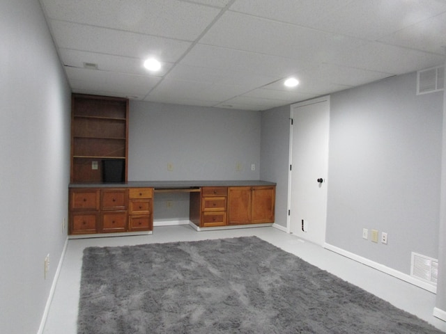 unfurnished office featuring light carpet, a drop ceiling, built in study area, and visible vents