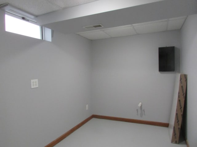 basement featuring visible vents, baseboards, and a drop ceiling