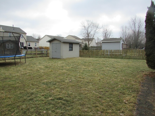 view of yard with a shed, a trampoline, a fenced backyard, and an outbuilding