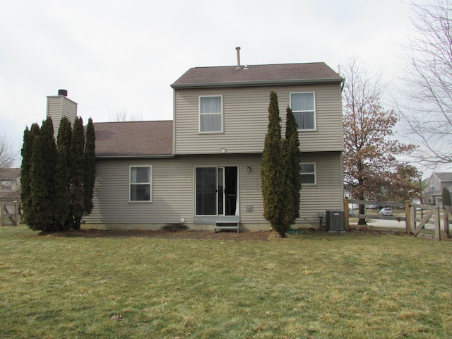 rear view of house featuring central air condition unit, a chimney, and a lawn