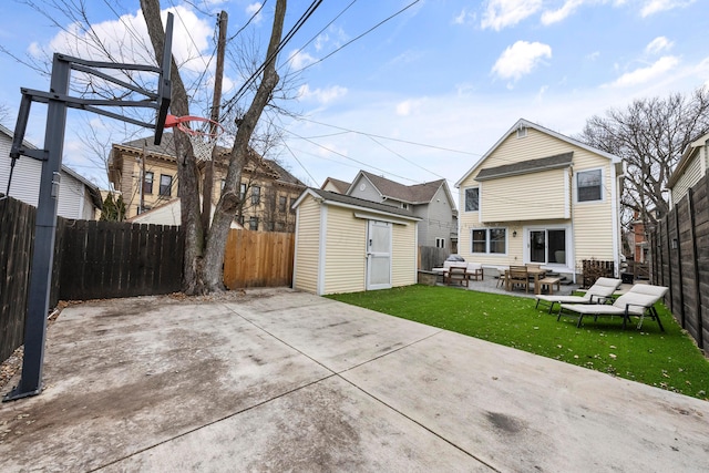 rear view of property with a lawn, a patio, a fenced backyard, an outbuilding, and a shed