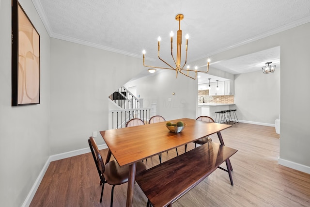 dining room with a chandelier, light wood finished floors, crown molding, and baseboards