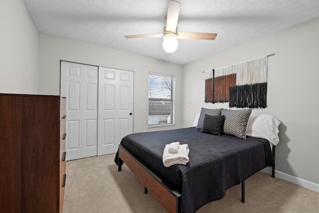 bedroom featuring ceiling fan, a textured ceiling, light carpet, baseboards, and a closet