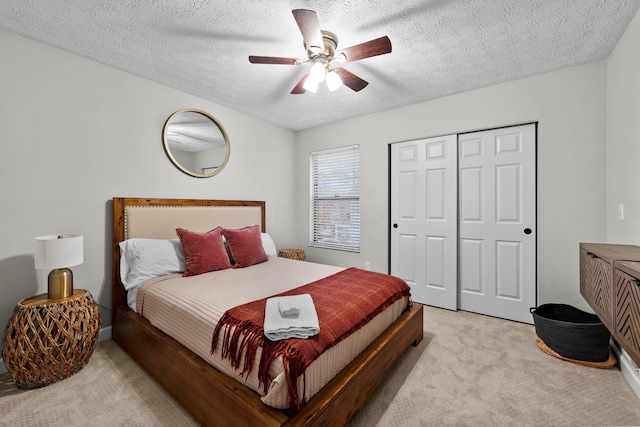 bedroom with a closet, light carpet, ceiling fan, and a textured ceiling