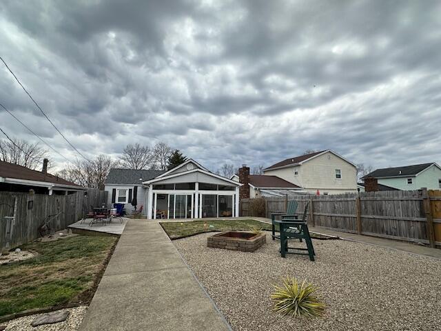 back of house featuring an outdoor fire pit, a patio area, a fenced backyard, and a sunroom