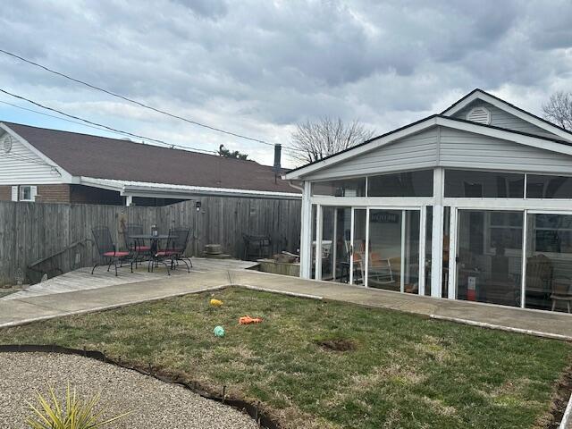 back of property featuring a sunroom, fence, a lawn, and a patio