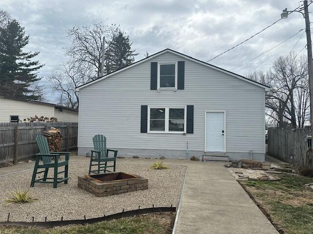 rear view of property featuring entry steps, fence, and an outdoor fire pit