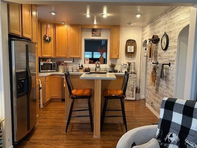 kitchen with dark wood-type flooring, refrigerator with ice dispenser, light countertops, and stainless steel microwave