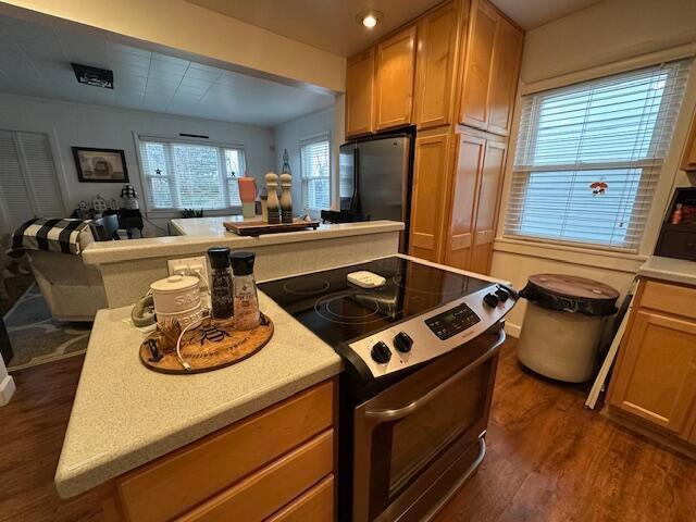 kitchen with dark wood finished floors, appliances with stainless steel finishes, open floor plan, a center island, and light countertops