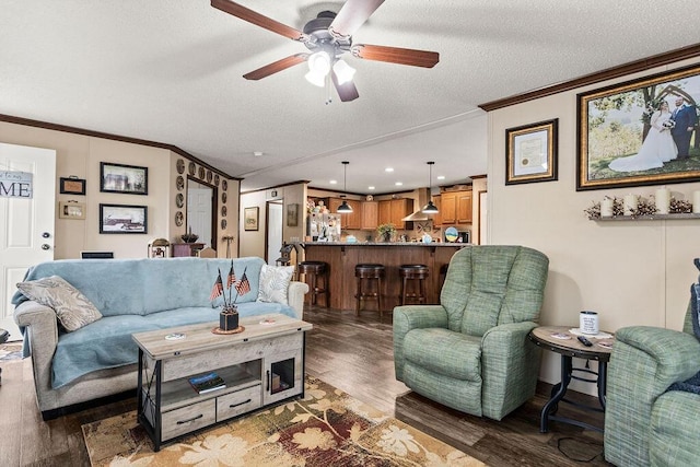 living area with ornamental molding, a ceiling fan, a textured ceiling, and wood finished floors