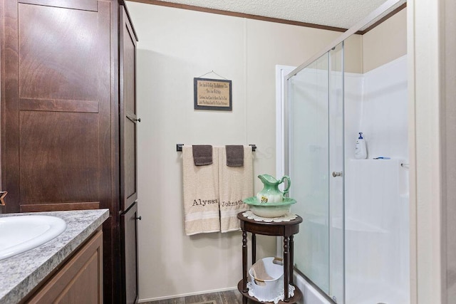 full bathroom featuring a stall shower, a textured ceiling, and vanity