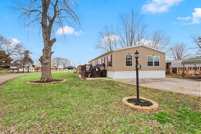 view of side of property featuring driveway, fence, and a yard