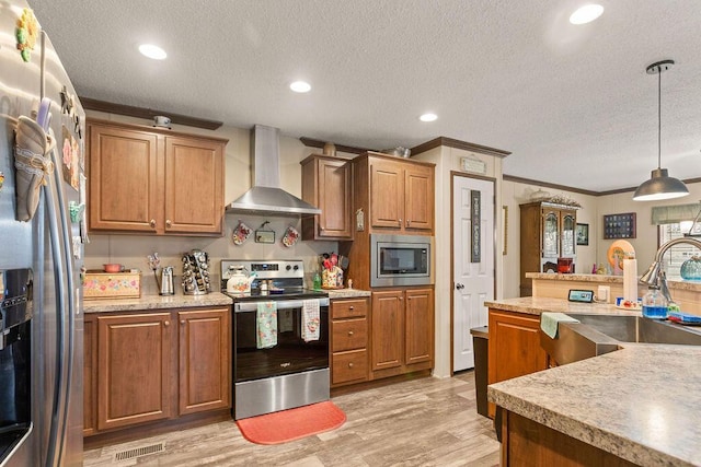 kitchen featuring light wood finished floors, visible vents, appliances with stainless steel finishes, wall chimney range hood, and a sink