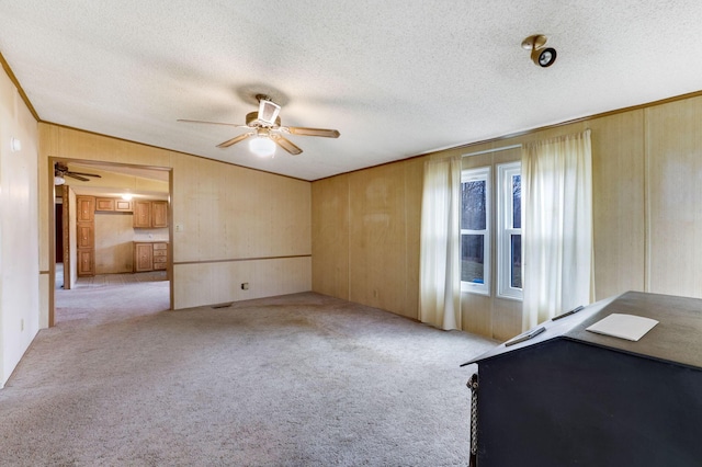 unfurnished bedroom with carpet floors, ornamental molding, a textured ceiling, and wooden walls