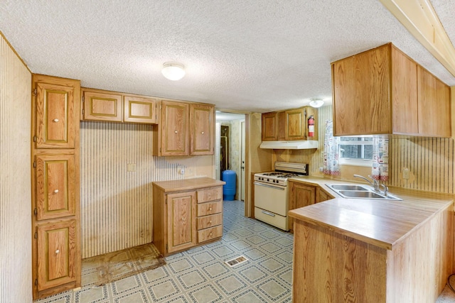 kitchen featuring a textured ceiling, a sink, light countertops, light floors, and gas range gas stove