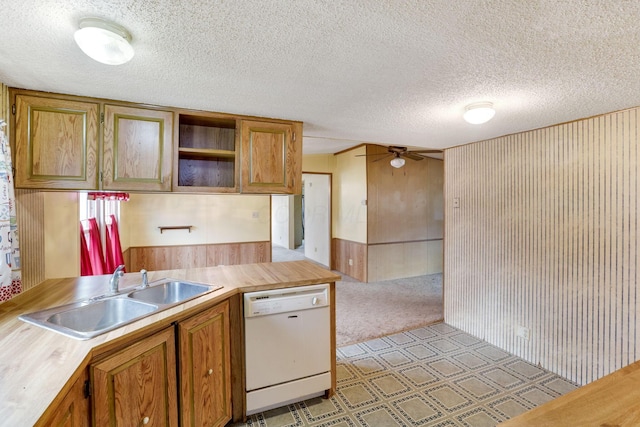 kitchen with brown cabinetry, a ceiling fan, white dishwasher, a textured ceiling, and a sink