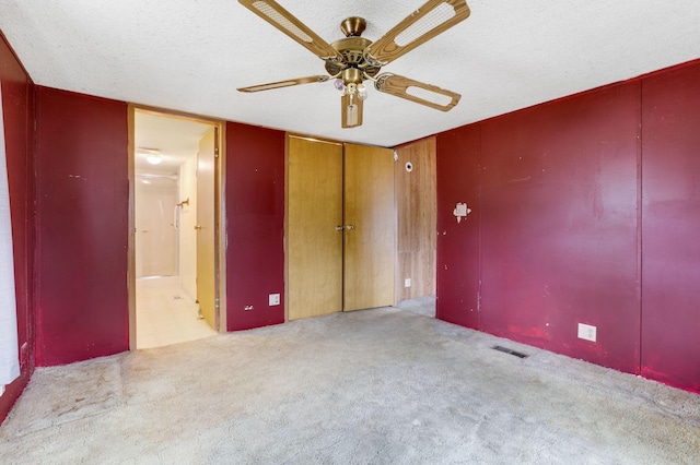 carpeted spare room with ceiling fan, visible vents, and a textured ceiling