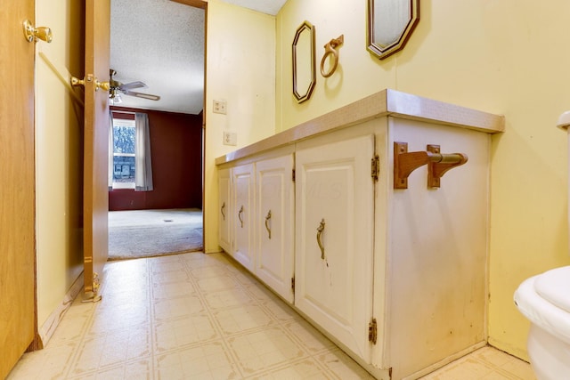 bathroom with a ceiling fan, a textured ceiling, and tile patterned floors