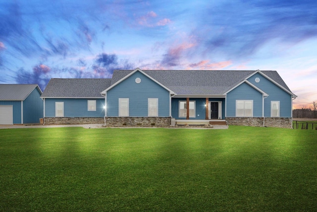 single story home with an outdoor structure, a front yard, and a shingled roof