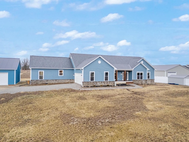 single story home featuring an outbuilding, stone siding, a garage, and fence