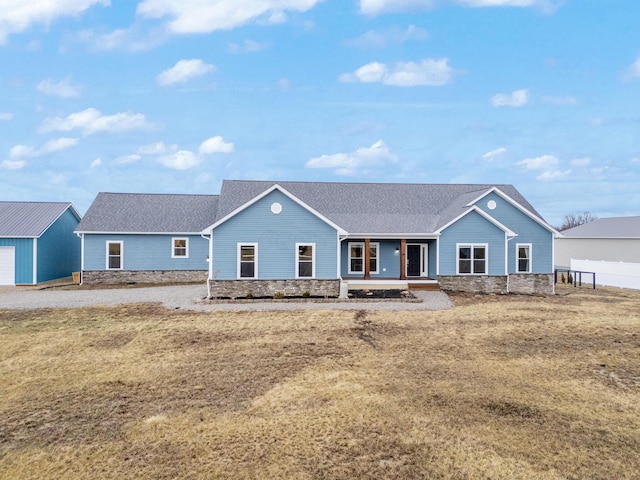 ranch-style home with stone siding, covered porch, and an outdoor structure