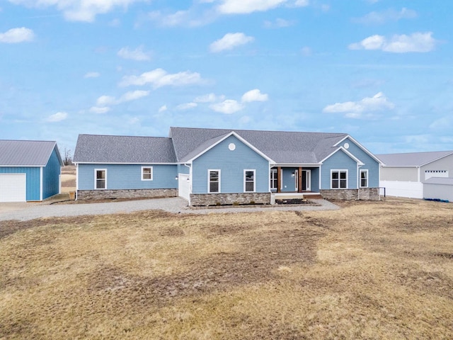 ranch-style home featuring an outdoor structure, a porch, fence, and a shingled roof
