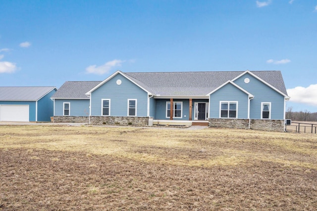 ranch-style home with fence, a shingled roof, a front lawn, an outdoor structure, and stone siding