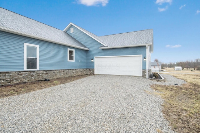 view of home's exterior featuring an attached garage, driveway, and a shingled roof