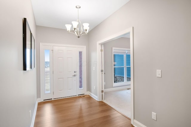 foyer entrance featuring baseboards, a notable chandelier, and wood finished floors