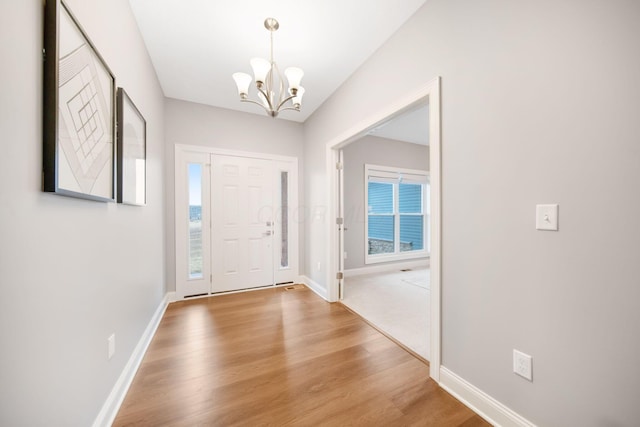 entrance foyer with light wood-type flooring, baseboards, and an inviting chandelier